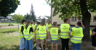Dzieci w odblaskowych kamizelkach WIOŚ na terenie szkolnym podczas zajęć z Inspektorem WIOŚ