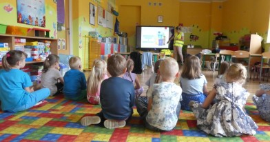 Najmłodsi uczestnicy prelekcji siedzą na dywanie podczas multimedialnej prezentacji