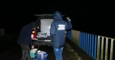 Inspektorzy ochrony Środowiska podczas czynności służbowych, wraz z pracownikami Centralnego Laboratorium Badawczego pobierają próbki zanieczyszczonej wody w rzece i wykonują badanie
