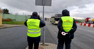 Inspektor Ochrony Środowiska i funkcjonariusz KAS podczas czynności służbowych przez lornetkę typują do zatrzymania auto z transportem