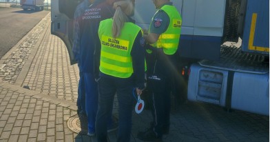 Inspektor Ochrony Środowiska  i funkcjonariusze służby celno skarbowej z kierowcą zatrzymanego pojazdu podczas kontroli dokumentacji