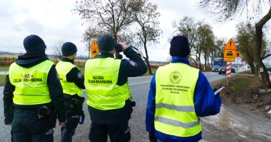 Inspektor Ochrony Środowiska i funkcjonariusze Służby Celno-Skarbowej w punkcie kontrolnym przy drodze obserwujący przemieszczające się pojazdy