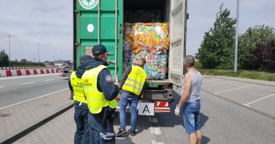 Inspektor Ochrony Środowiska wraz z funkcjonariuszami Służby Celno - Skarbowej podczas oględzin przewożonych odpadów w naczepie tira..