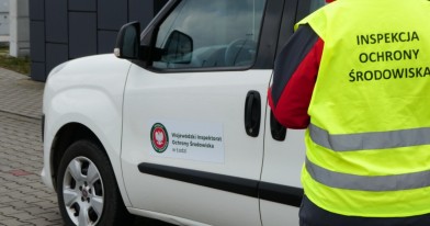 Inspektor stojący przy oznakowany samochodzie Wojewódzkiego Inspektoratu Ochrony środowiska w Łodzi