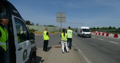 Inspektorzy Inspekcji Transportu Drogowego i Inspekcji Ochrony Środowiska obserwujący w punkcie kontrolnym ruch na autostradzie. 