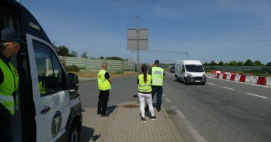 Inspektorzy Inspekcji Transportu Drogowego i Inspekcji Ochrony Środowiska obserwujący w punkcie kontrolnym ruch na autostradzie.