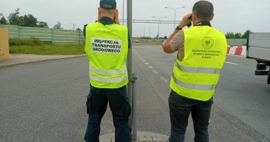 Inspektor Inspekcji Transportu Drogowego oraz Inspektor Ochrony Środowiska, stojący przy drodze krajowej podczas czynności kontrolnych
